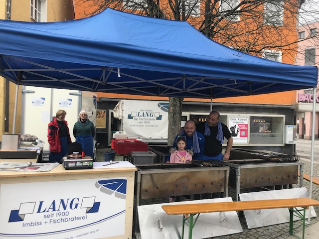 Die Familie Lang am Fischbraterei-Stand mit dem LANG-Firmenlogo