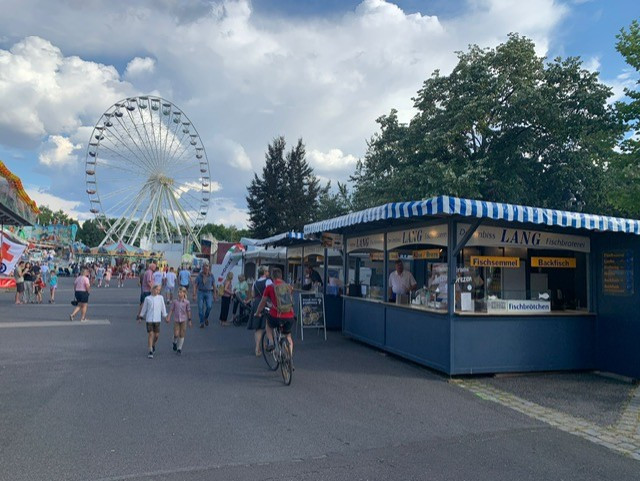 Fischbraterei Lang Stand auf dem Volksfest mit Riesenrad im Hintergrund